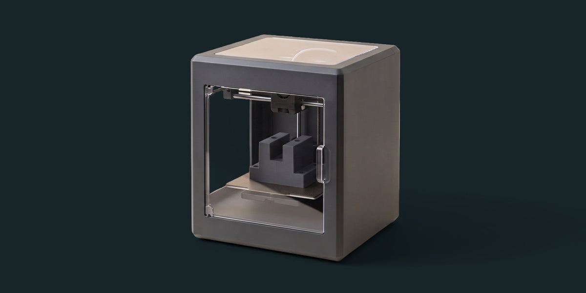 Kapağı kapalı, içinde antrasit bir parça basılmış kapalı hazneli masaüstü 3D yazıcı